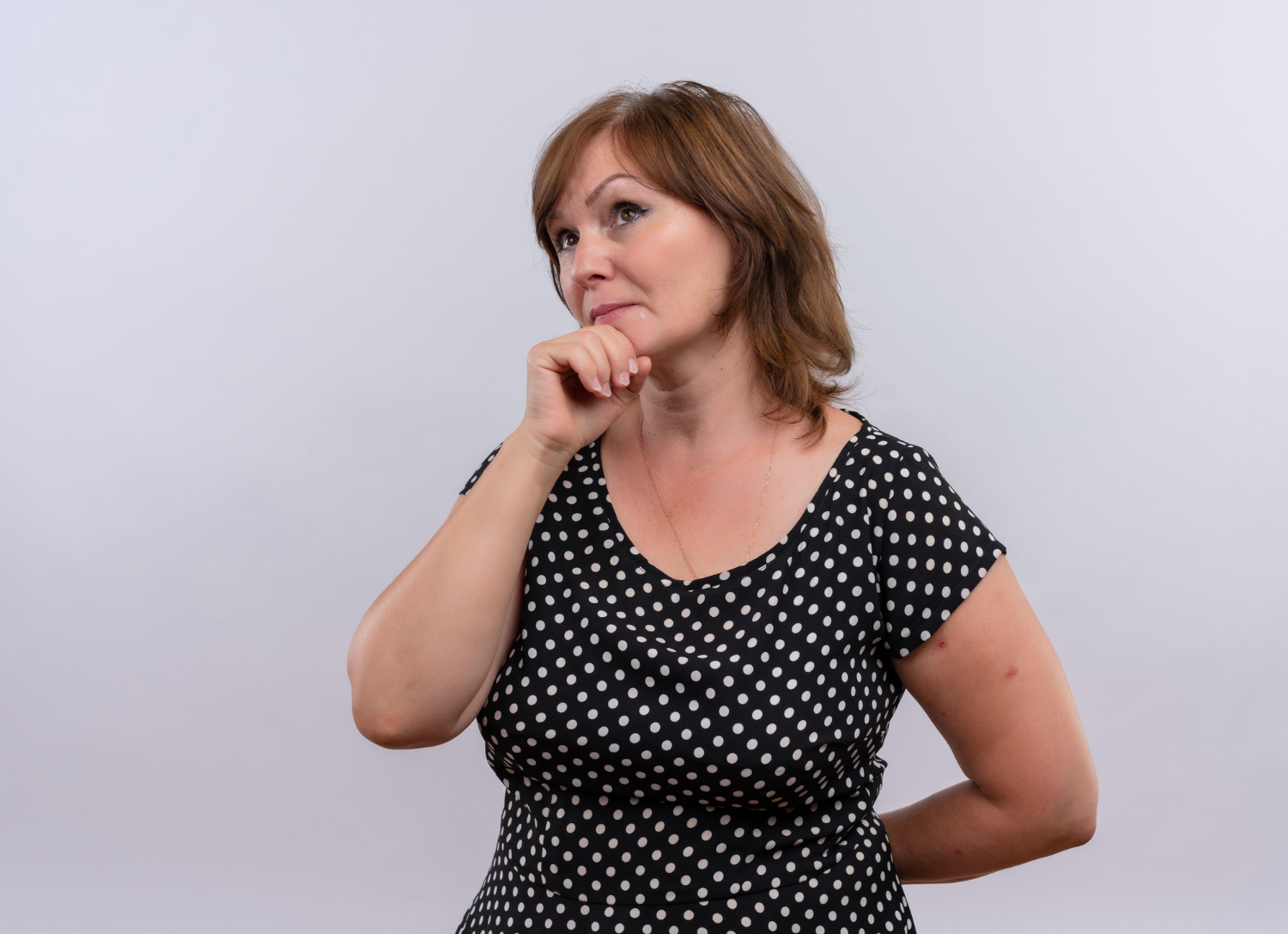 thoughtful-middle-aged-woman-putting-hand-chin-isolated-white-wall